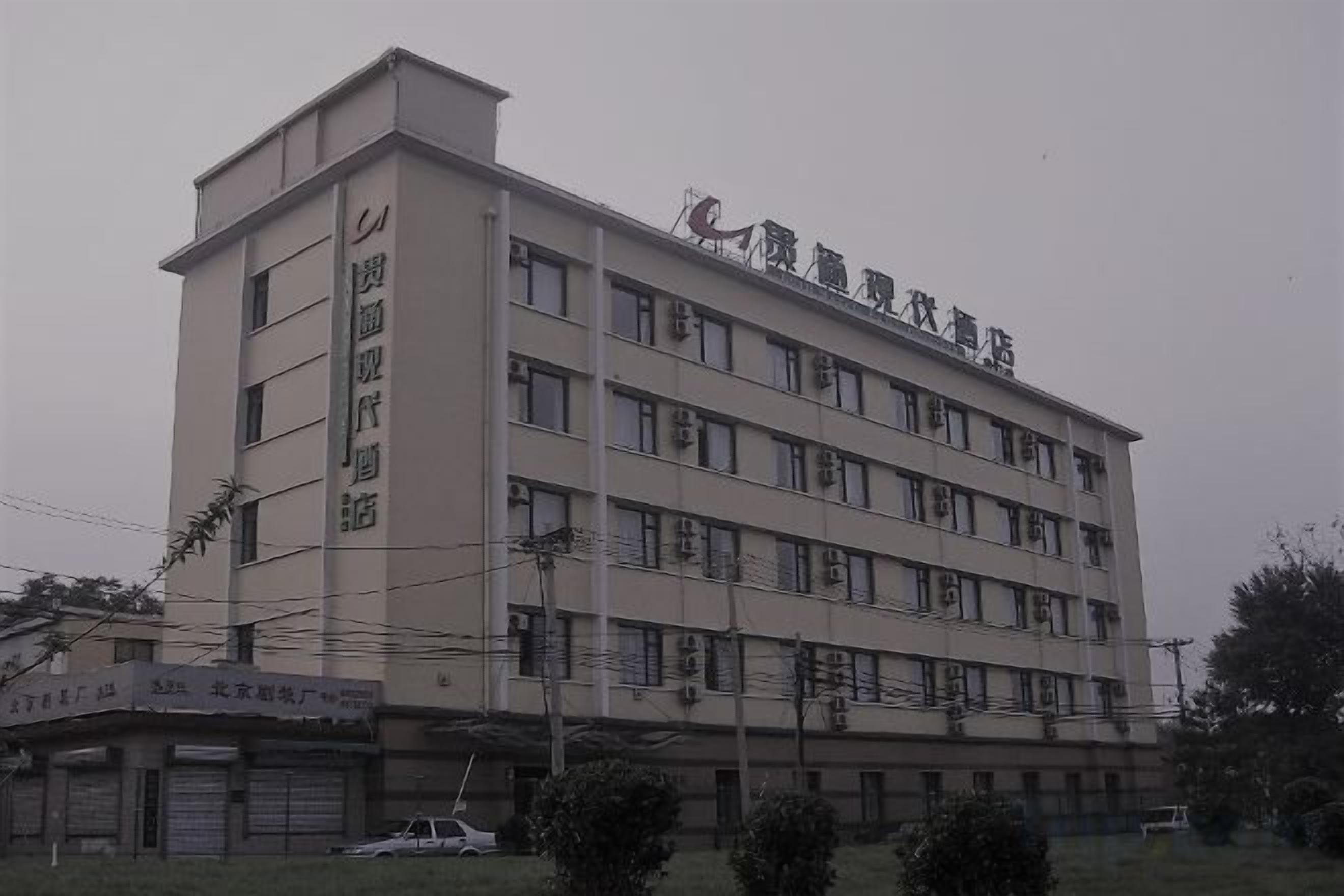 A multi-story building with a flat roof and a sign indicating it is a hotel.