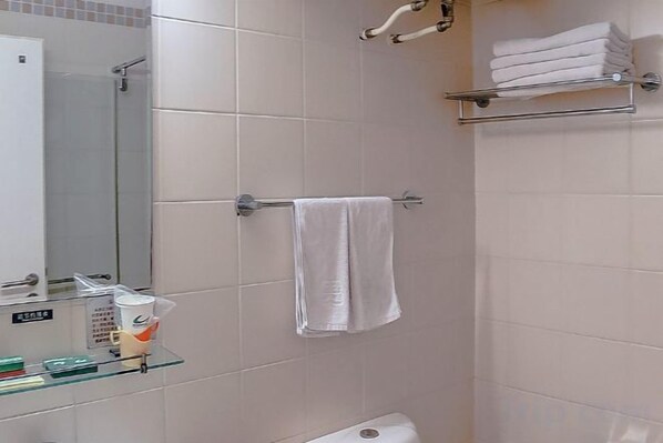 A bathroom with a glass shelf holding toiletries, a towel hanging on a rack, and a toilet.