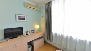 Habitación de hotel con televisión, escritorio, lámpara y cortinas.