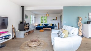 A modern living room with a white sofa, a blue sofa, a TV, and a fireplace.