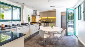 A modern kitchen with a central island, white cabinetry, and a dining area with a round table and chairs.