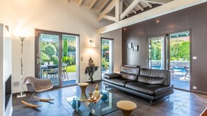 A spacious living room with a leather sofa, a glass coffee table, and a rocking chair.