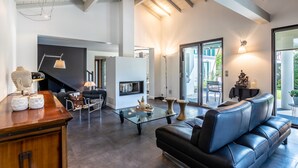 A modern living room with a glass coffee table, leather sofa, and a fireplace.