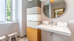 A modern bathroom with a large mirror, a white sink, and a wooden cabinet. - Romy - En centre-ville (Biarritz)