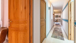 A hallway with wooden doors, a patterned rug, and a seating area with cushions. - Romy - En centre-ville (Biarritz)