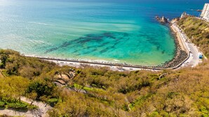 An aerial view of a coastal area with a clear road leading to a beach, surrounded by greenery and a building on the right. - Sunset - Vue exceptionnelle sur l'océan (Biarritz)