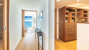 A modern interior with a wooden floor, a hallway leading to a balcony, and a built-in wardrobe with multiple shelves. - Sunset - Vue exceptionnelle sur l'océan (Biarritz)