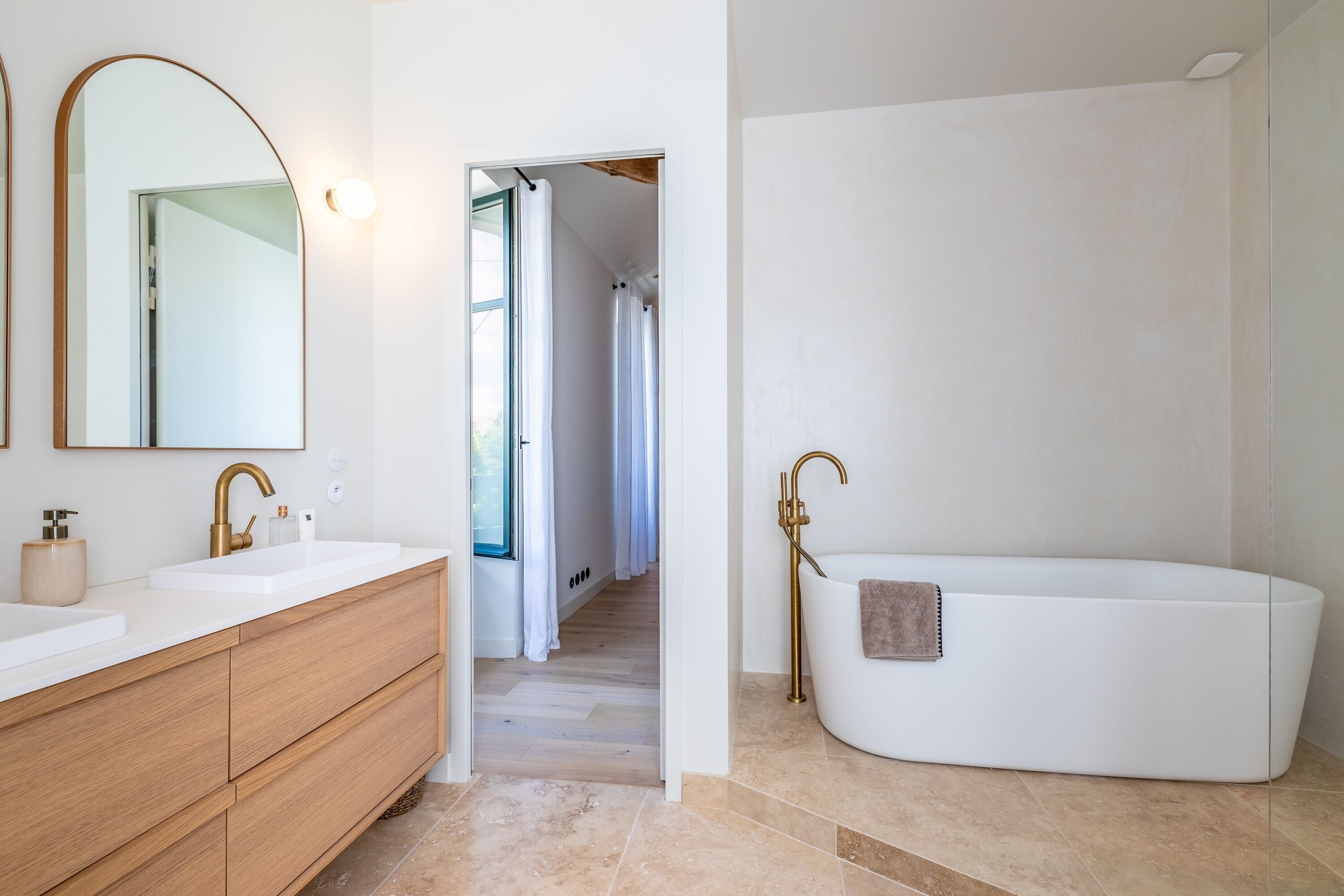 Ein modernes Badezimmer mit einem großen Spiegel, zwei Waschbecken, einer Badewanne und einem Holz-Waschtisch.