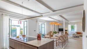 Une cuisine moderne dotée d’un îlot central, de grandes fenêtres et d’un coin repas avec des chaises et une table.