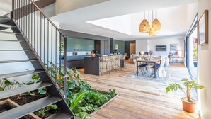 A modern interior with a staircase, wooden flooring, a kitchen area, and a dining space. - Villa Loreteian - Splendide villa au calme (Ahetze)