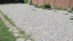 A gravel driveway leading to a brick building with a tiled roof. - Room 5 (Huancayo)