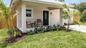 A single-story house with a front porch, a black door, and a small window. - Pet Friendly 2bed/2bath coastal hideaway (Jensen Beach)