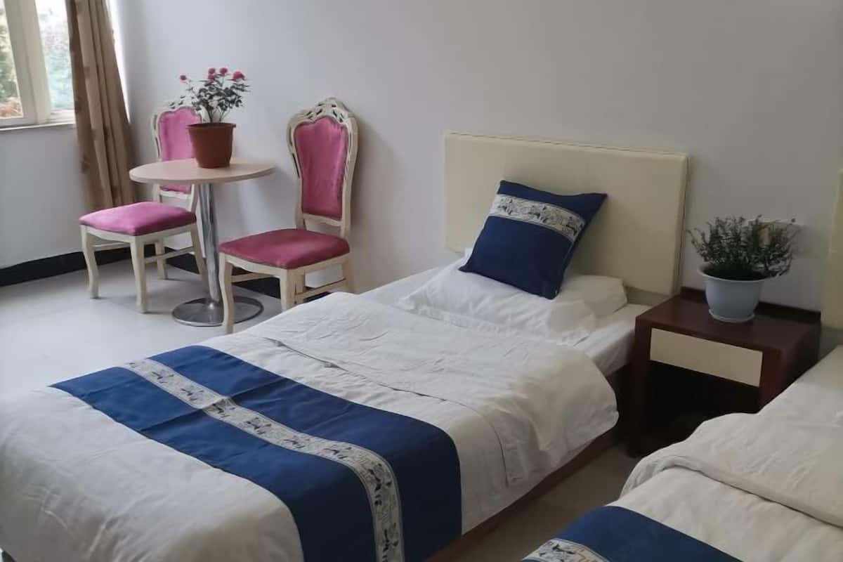 Una habitación de hotel con una cama, una silla, una mesita y una planta en maceta.