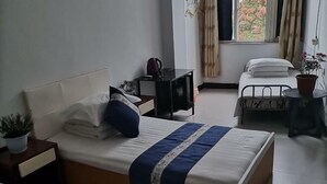 A bedroom with a bed, bedside tables, a window with curtains, and a potted plant.