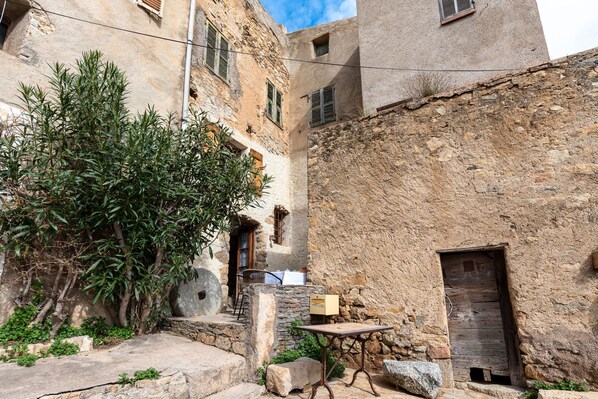 A narrow alley with stone buildings, a wooden door, and a table with a box on it.