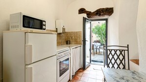 Une cuisine compacte équipée d’un four à micro-ondes, d’un four traditionnel et d’une petite table avec une chaise.