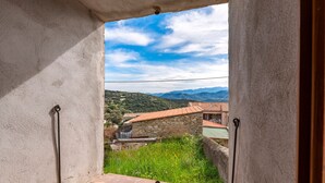 Un balcon donnant sur un bâtiment en pierre et sur des montagnes au loin.