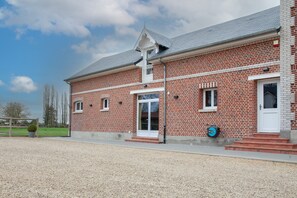 A red brick building with a white door and windows, a gravel driveway, and a clear sky. - Le Cheval Blanc - Proche Amiens, grand jardin (Damery)
