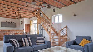 A modern living room with a blue sofa, a glass coffee table, and a wooden staircase. - Le Cheval Blanc - Proche Amiens, grand jardin (Damery)