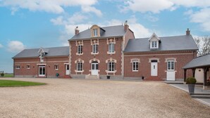 A large, multi-story brick building with a symmetrical facade, multiple windows, and a gravel driveway. - Le Cheval Blanc - Proche Amiens, grand jardin (Damery)
