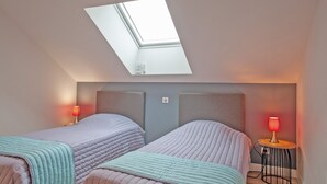 A bedroom with two beds, a skylight, and a bedside table with a lamp. - Le Cheval Blanc - Proche Amiens, grand jardin (Damery)