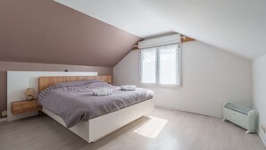 Un dormitorio con cama, mesita de noche, lámpara, ventana y radiador.