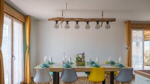 Comedor con mesa de madera dispuesta para seis personas, rodeada de sillas de varios colores.