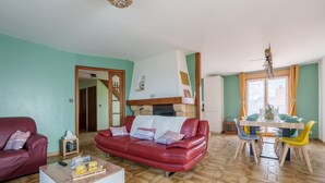 Una sala de estar con un sofá de cuero rojo, una mesa de centro de madera y un comedor con mesa y sillas.