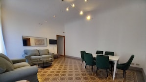 Un salon avec un sol à motifs, un canapé, une table basse et un coin repas comprenant des chaises et une table.
