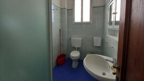 Une salle de bain avec des toilettes, un lavabo et une fenêtre.