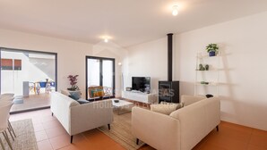 A modern living room with two sofas, a coffee table, a TV, and a fireplace. - Villa Terracota by Acasadascasas (Mafra)