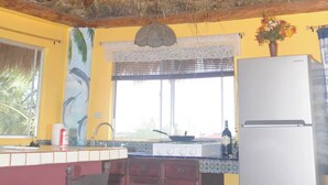 Una cocina con techo de paja, ventilador de techo y refrigerador.
