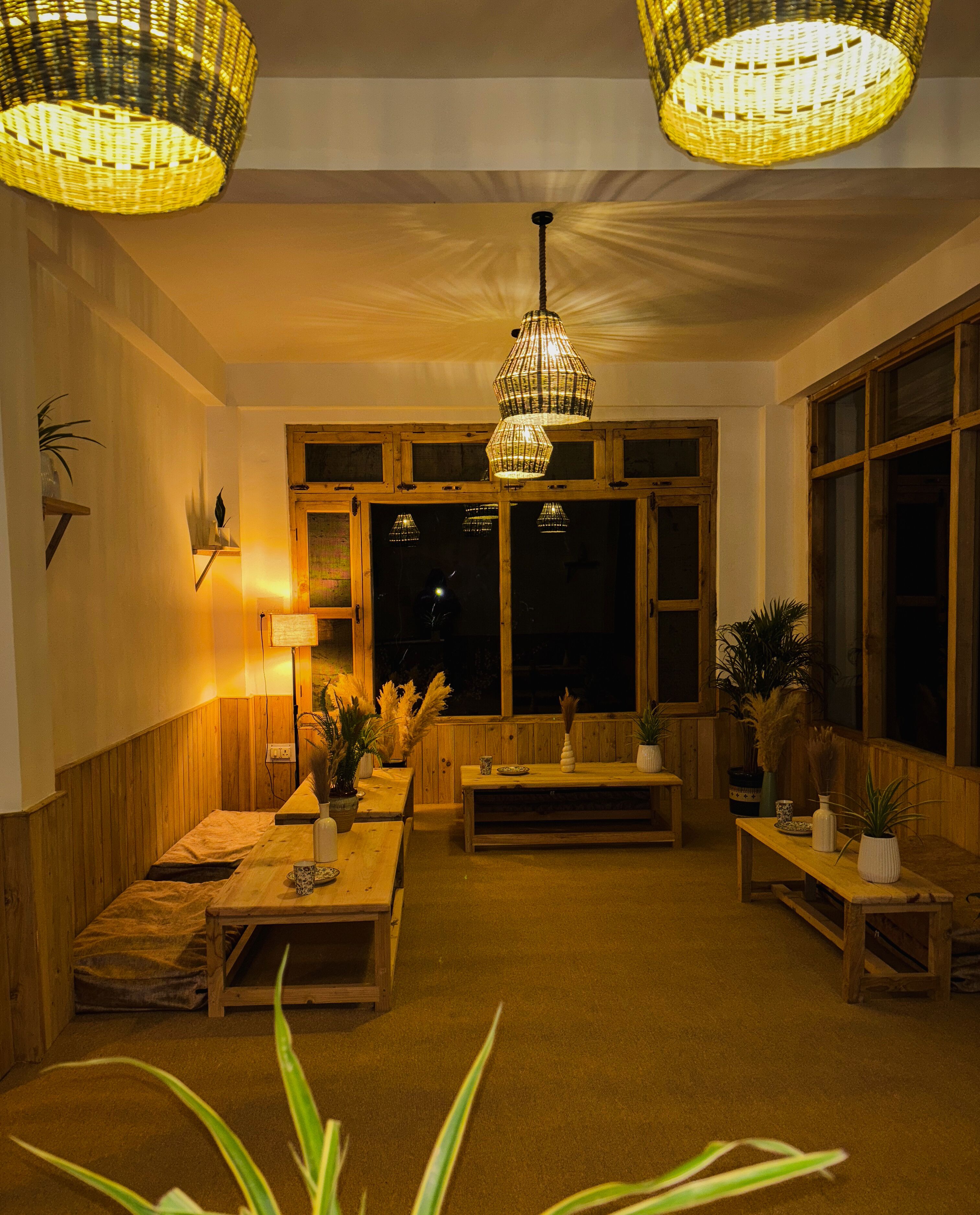 A cozy room with wooden furniture, a large window, and a hanging light fixture.