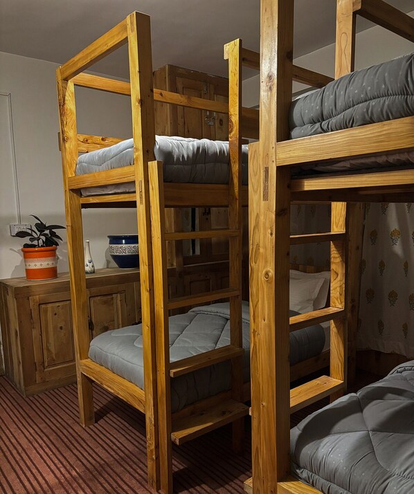 A bunk bed room with wooden frames, a potted plant, and a bowl on a table. - The Woods - Tirthan Valley (Banjar)