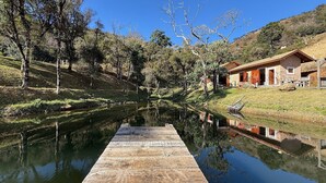 A wooden dock extending into a calm river, surrounded by trees and a hillside.
