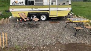 A camper with a kitchen area, a dining table, and outdoor seating.