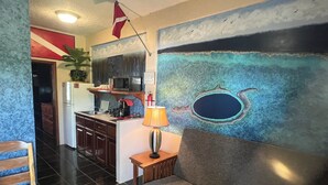 A modern kitchen with a microwave, sink, and cabinets. There is a dining area with a table and chairs. A flag is hanging on the wall. - DIVING ROOM - Close to Beach - One Bedroom Suite (San Pedro)