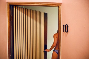 Una persona en traje de baño entrando a una habitación con una puerta de listones de madera y el número 10 en la pared.
