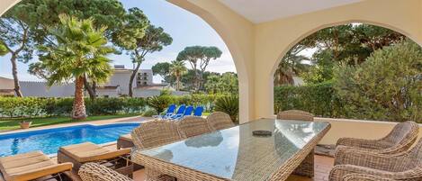 Relax in a tranquil outdoor space surrounded by lush greenery and a swimming pool.