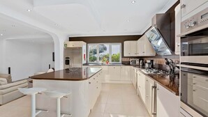 A modern kitchen with a central island, stainless steel appliances, and a large window providing a view of greenery.