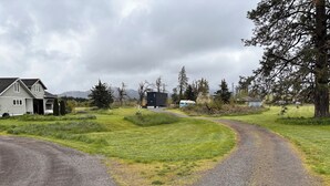 A gravel driveway leading to a house with a garage, surrounded by grassy fields and trees. - Charming 2-bedroom attached apartment with AC, WiFi in adorable Creswell (Creswell)