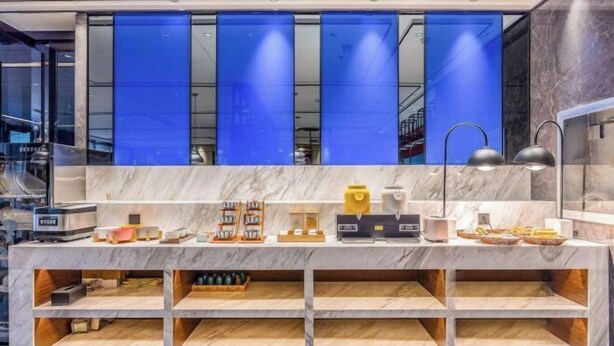 A modern reception desk with a marble top and blue partitions, featuring a coffee machine, tea station, and various snacks. - Super 8 Collection Hotel (Lanzhou Railway Station Hongxingxiang Subway Station) (Lanzhou)