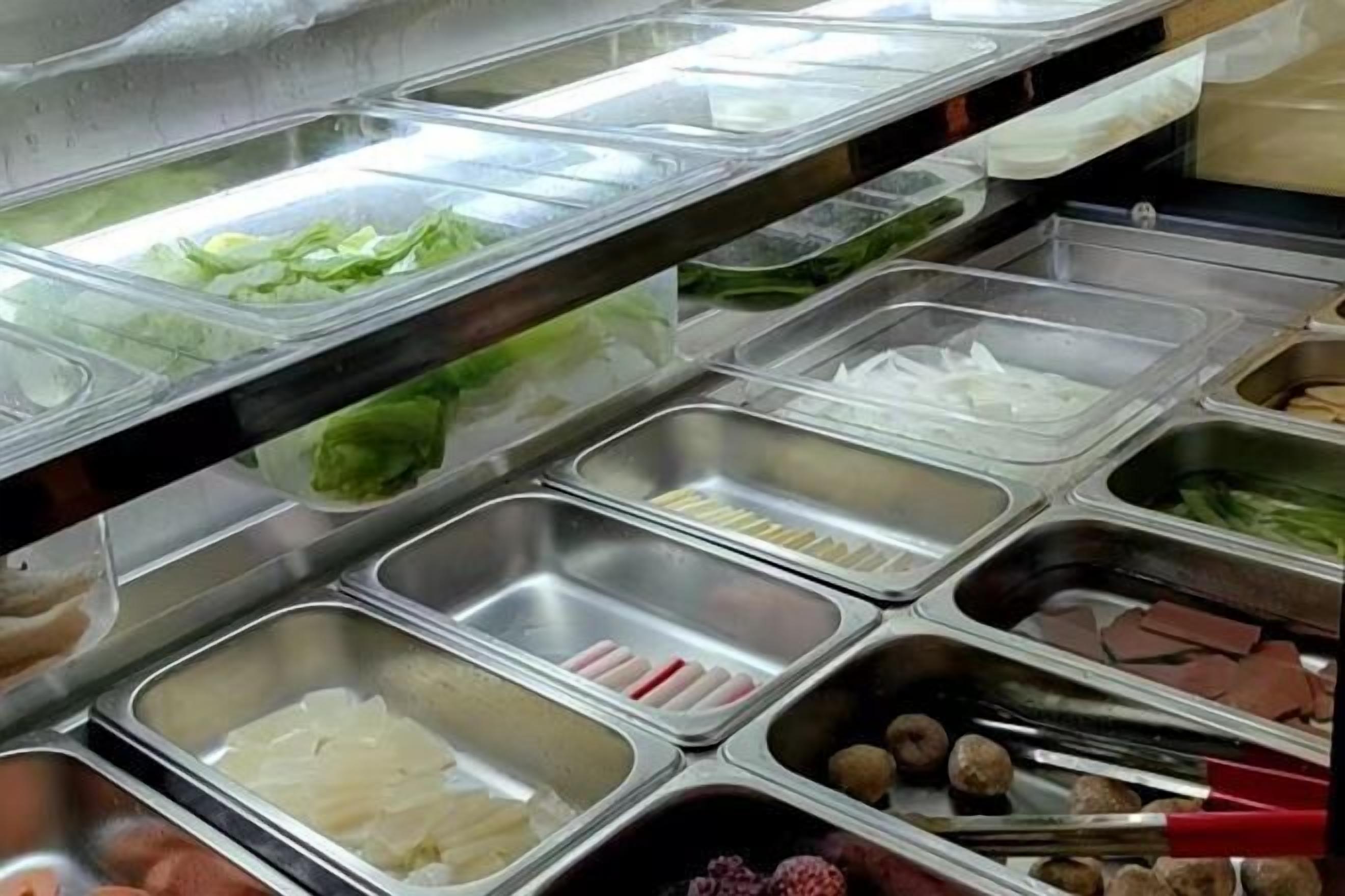A buffet with various food items including vegetables, meats, and other dishes in separate compartments.