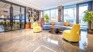 A modern lobby with a seating area, a bookshelf, and a large window. - Super 8 Collection Hotel (Lanzhou Railway Station Hongxingxiang Subway Station) (Lanzhou)