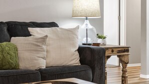 A living room with a dark sofa, a lamp, and a small table with a plant. - 3BR Condo | Walk-In Access | Sleeps 11 (Branson)