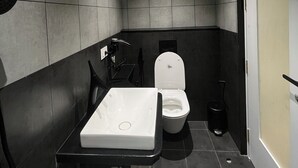 A modern bathroom with a toilet, sink, and shower. - The Old City (Kanchipuram)