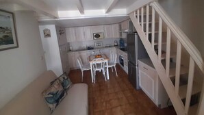 Une cuisine de taille réduite avec des meubles blancs, une table à manger avec des chaises et un réfrigérateur.