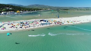 Vista aérea de una playa con numerosos parasail de colores, una playa de arena y un mar azul claro.
