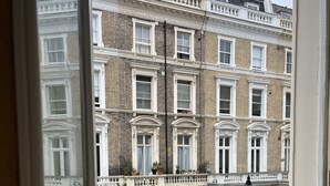 Blick auf eine Reihe traditioneller Backsteinreihenhäuser mit weißem Zierrat und zahlreichen Fenstern, einen Balkon mit Geländern und eine Straßenlaterne.
