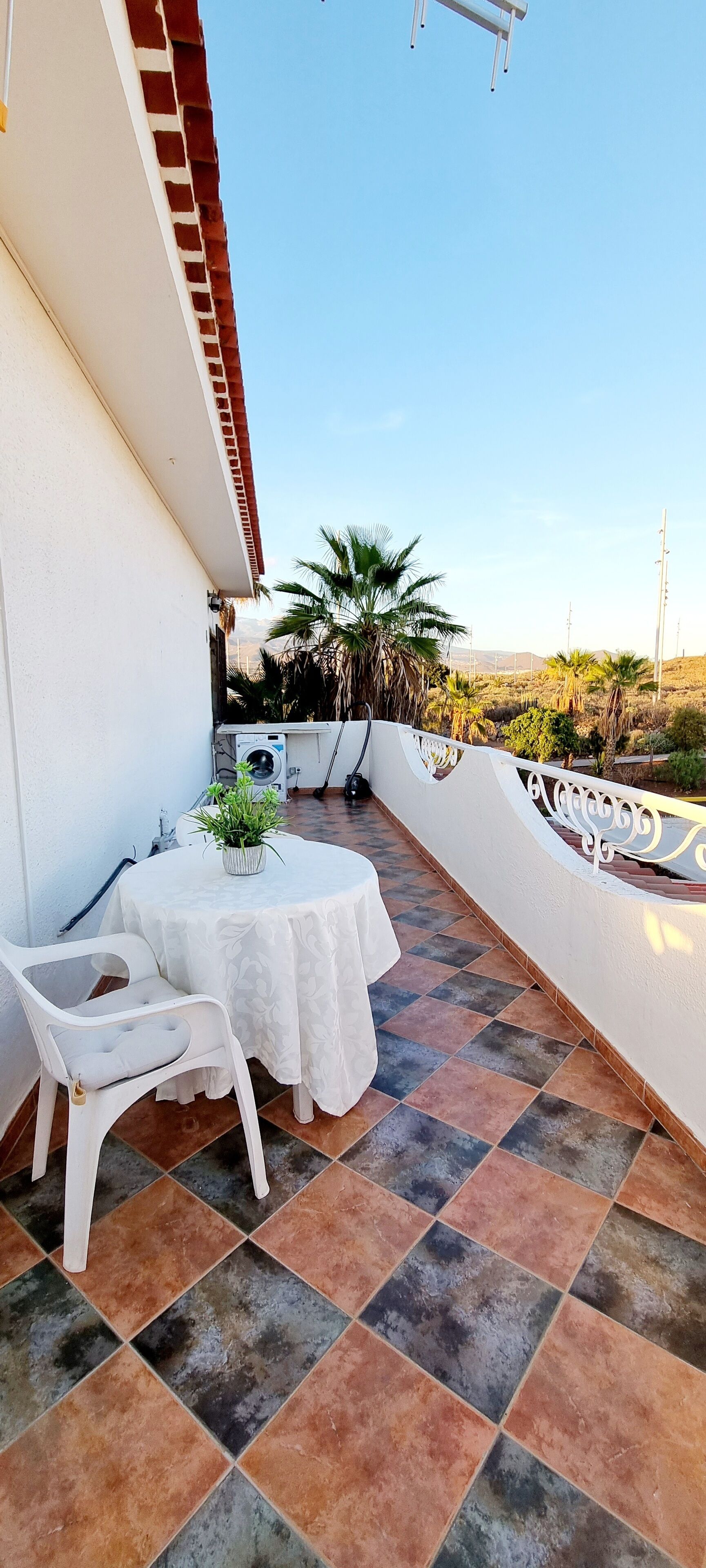 A patio with a round table and chairs, a washing machine, and a potted plant.